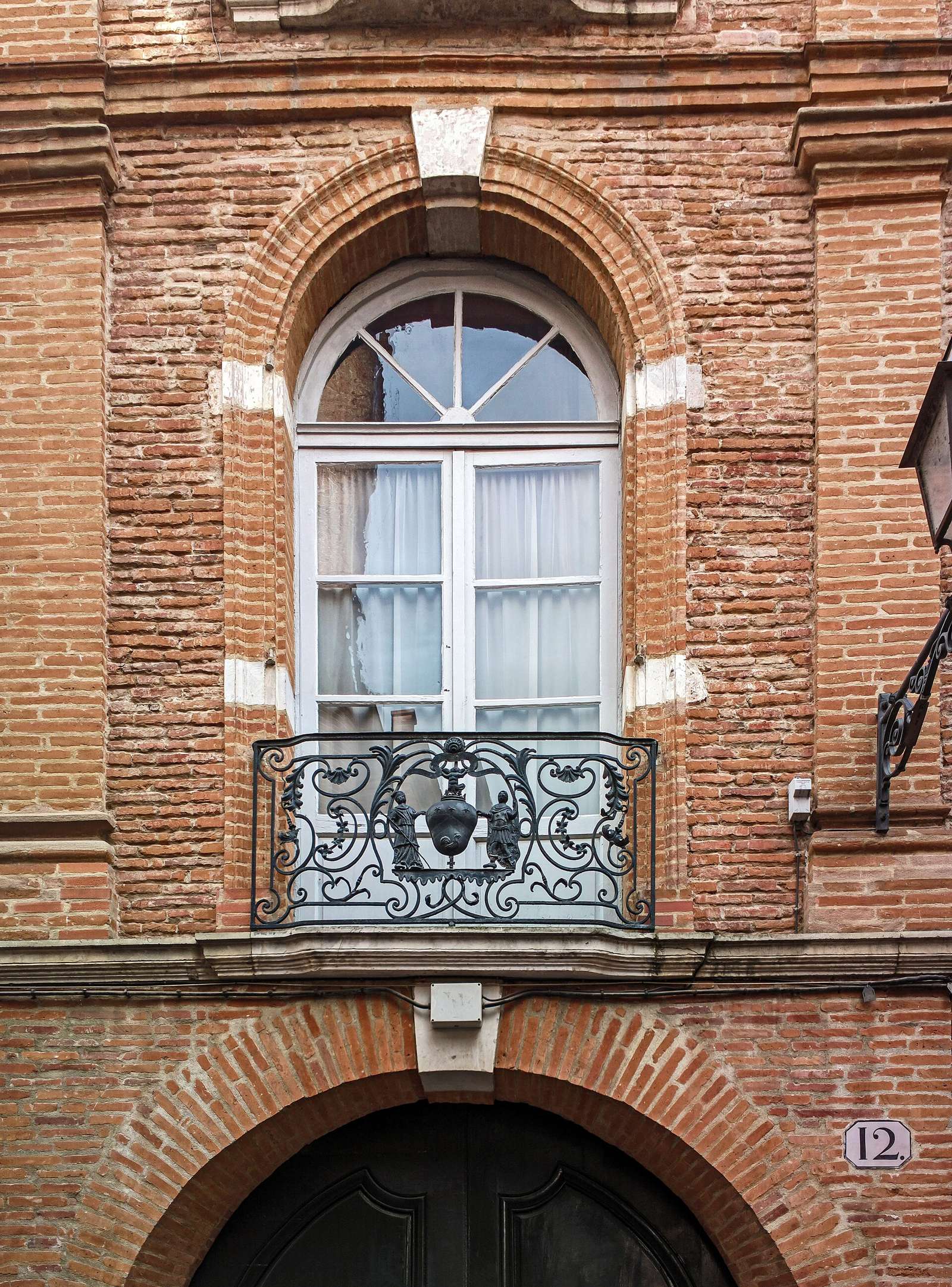 Porte cochère, fenêtre et balcon en fer forgé sur une façade de brique du XVIIe siècle, 12 rue Vélane à Toulouse